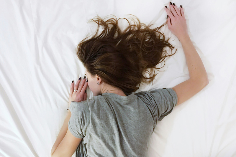 Woman lying sick on bed