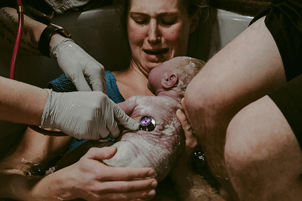 Woman holding baby after birth in water